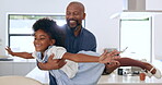 Family, flying and a girl in the arms of her father for love in the kitchen of their home together. Smile, fantasy plane or imagination games with a black man parent and girl child in their apartment