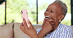 Phone, video call and senior black woman on a sofa laughing and talking in the living room at home. Technology, online and elderly female person in retirement on virtual conversation with cellphone.