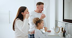 Dental, oral care and a family brushing teeth in the bathroom of their home together for morning routine. Toothbrush, toothpaste or hygiene with a mother, father and daughter cleaning their mouth