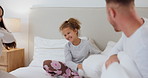 Bedroom, pillow fight and child with parents playing for love, bonding and loving relationship. Family, home and happy mother, father and young girl with pillows for playful, games and relax on bed