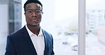 Face, corporate and a serious black man at a window in his office for professional work or career. Portrait, business and glasses with a confident young employee in a suit at his workplace in the day