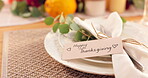 Thanksgiving, dinner and festive table for fine dining with plate, card and note to welcome guest. Happy, event and setting for party, celebration or catering for meal in home, house or apartment