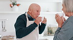 Senior couple, drinking coffee and kitchen in the morning with relax, conversation and love in a home. Retirement, marriage and blowing hot drink or tea together with a smile and happy in a house