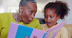 Grandmother, kid and reading books for surprise, language development and learning knowledge at home. Senior woman, child and black family relax for storytelling, shock or wow for fairytale in lounge
