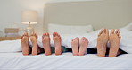 Sleeping, feet and family wake up in a bed with toes, movement and morning energy in their home together. Love, foot and children awake with parents in a bedroom for nap, dreaming or resting in house