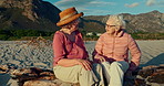 Senior women, friends and talk at beach on rocks, memory and conversation with reunion on holiday. Elderly lady, people and nature with smile, chat and relax with freedom, vacation and retirement