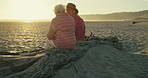 Elderly women, friends and talk at beach on wood log, memory and conversation for reunion with sunset. Senior lady, people and nature with back, chat and relax with freedom, vacation and retirement