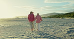 Senior women, back and vacation on beach, bonding and walking on sand or relaxing on holiday. Elderly friends, love and holding hands for support in retirement, conversation and traveling in outdoors