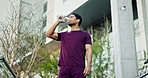 Man, fitness and drinking water in city for sports break, energy and workout performance. Thirsty athlete, asian runner and bottle for hydration, nutrition and healthy recovery for exercise outdoor