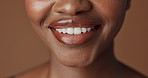 Closeup, lips and black woman with beauty, smile and skincare on a brown studio background. African person, girl and model with gloss, cosmetics and dermatology with clear skin, smooth and aesthetic