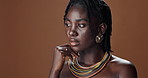 Face of black woman, skincare or model thinking of wellness, necklace or healthy beauty in studio. Dermatology, dreadlocks or African person with glow, idea or natural aesthetic on brown background 