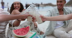 People, toast with drinks bottle at beach for celebration, outdoor party and new year holiday with fruits. Happy group of friends with watermelon, soda or ginger beer and cocktail for cheers at ocean