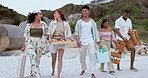 Picnic, happy and group of friends at the beach on vacation, adventure or holiday together. Conversation, fun and young people with basket of food or snacks walking on sand for summer weekend trip.