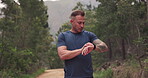 Man, running or smart watch in forest for fitness, cardiovascular results or workout performance on clock. Runner, sports gear or check timer, stopwatch and exercise progress in woods, nature or park