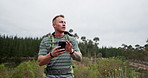 Phone, search and man hiking in a forest with travel, guide or navigation, directions or walking in nature. Smartphone, map and male backpacker with app for compass, location or tracking adventure