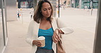 Mature hispanic woman checking the time drinking coffee in the city