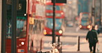 Two red busses driving through London with people walking by