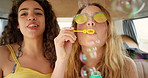 Two beautiful friends happily blowing bubbles together having fun