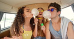 A group of friends having fun blowing bubbles together in their camper van during a holiday