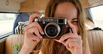 A cheerful young woman taking photos in the back of her van during a roadtrip vacation