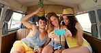 A group of friends being silly taking selfies with props in the back of their van during a roadtrip