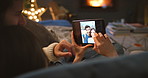 A young man and woman affectionately cuddling and looking through images on their tablet