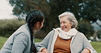 Caregiver helping woman with disability in park for support, trust and care in retirement. Nurse talking to happy senior patient in wheelchair for rehabilitation, therapy and conversation in garden