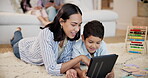 Education, tablet and mother teaching son on floor of living room in home together for child development. Love, smile or happy with parent and boy in apartment to study or complete school homework