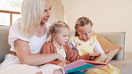 Mother, girl children and book on sofa for reading, learning and development with care, love and bonding. Mom, kids and storytelling with teaching, support and talk together on lounge couch in house