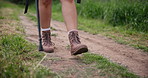 Legs, trail or shoes of man hiking, camping or walking on holiday vacation or weekend break at countryside. Footwear, closeup or camper trekking in woods outdoors, nature or natural park with stick