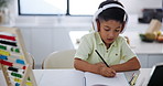 Boy, book and writing with headphones and tablet for online education, course and math at home. Distance learning, technology and audio with test for education, kid student studying and elearning