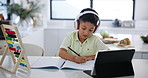 Boy, notebook and writing with headphones and tablet for online education, course and math at home. Distance learning, technology and audio with test for education, kid student studying and elearning