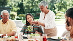 Food, thanksgiving and grandparents with family or child at table outdoor for celebration or tradition. Salad, sharing or lunch with people, grandma and kid eating meal together in a social gathering