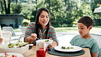 Family, thanksgiving vegetables and mother with son at table outdoor for celebration or tradition. Love, food or lunch with woman parent and boy child eating meal together at social gathering