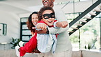 Happy family, parents and play with superhero kid in home, having fun and laughing together. Father, mother and child in costume for game, freedom and African boy excited to pretend in action mask