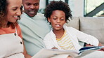 Parents, child and reading book for learning and bonding, storytelling and support in knowledge. Black family, boy and relaxing on couch and literacy development, language and conversation at home