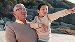 Child, pointing and grandfather on beach with love, talking and happy to play on summer vacation. Old man, smile or bonding together in care, travel adventure or sunset leisure by seaside on holiday