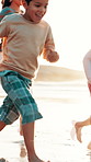 Family, game and running on beach at sunset with happiness, energy and travel on holiday. Summer, vacation and parents bonding, playing and catch children on sand together with fun at sea or ocean