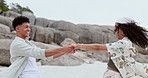 Holding hands, love and couple playing at the beach on vacation, adventure or holiday together. Happy, smile and young woman and man having fun and bonding by the ocean or sea on weekend trip.