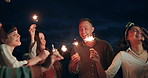 Happy friends, sparkles and night in celebration for party, new years or outdoor event together. Group of people smile and dancing with fireworks in late evening for friendship, memory or fun moment