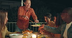 Friends, night and man with knife for chicken on patio, happy or talk for food at new years eve party. Women, group and cutting at table for chat, memory or giving plate for meat, diversity or event