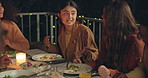 Friends, talking and dinner in night, patio and happy for conversation, food and new years eve celebration. Woman, men and group at table with chat, laughing and party with story, diversity and event