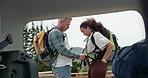 Happy couple, forest and backpack by car for hiking or travel on outdoor adventure together. Man and woman tourist or hiker getting bag ready by vehicle for trekking, camping or journey in nature