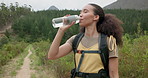 Hiking woman, drinking water and bottle in nature for hydration, detox or wellness on bush adventure. Girl, trekking and liquid for health in forest, woods and outdoor for fitness, exercise or summer