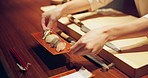 Hands, sushi chef and presentation in restaurant on table at diner, cuisine or expert cooking in night. Person, kitchen or fish with catering, plate and service for nutrition, diet or snack in Japan