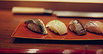 Closeup, sushi and food in night on restaurant table for cuisine, presentation or catering with fish meal. Plate, menu or diner with soy sauce, ready and service for nutrition, diet or snack in Tokyo