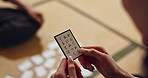 Hands, cards and Japanese game in closeup for challenge, contest and problem solving with clue. People, board and info for karuta for competition with paper, reading or play together to relax in home