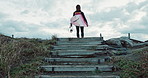 Back, woman and surfboard at beach, view of sea with stairs and ready for fitness in wet suit, sports and surfing in nature. Exercise, professional surfer or hobby with challenge, horizon and nature