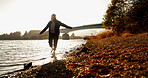Person, silhouette and river with walk, sunrise and nature in morning with freedom, game and balance. Woman, girl and feet in water, lake and steps with bridge, forest or woods with sunshine by trees