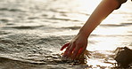 Closeup, hand and water in morning by ocean with touch, waves and nature on vacation in sunshine. Person, fingers and outdoor vacation by river, lake and sunrise in environment with ripple in Japan